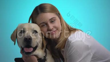 微笑的女人拥抱可爱的拉布拉多犬，看着相机，宠物是最好的朋友